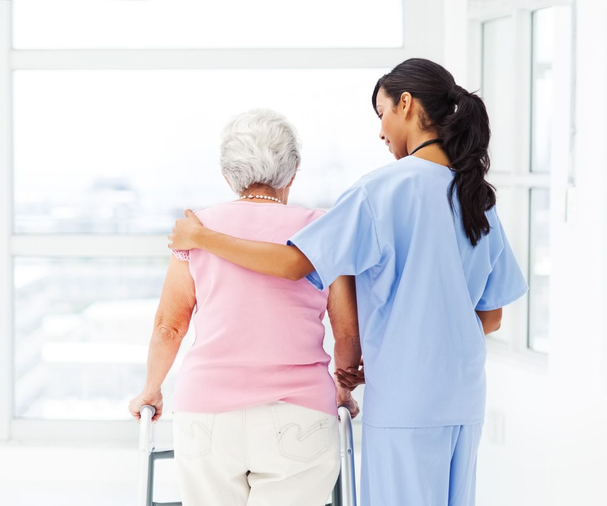Caregiver helping elderly woman with walker