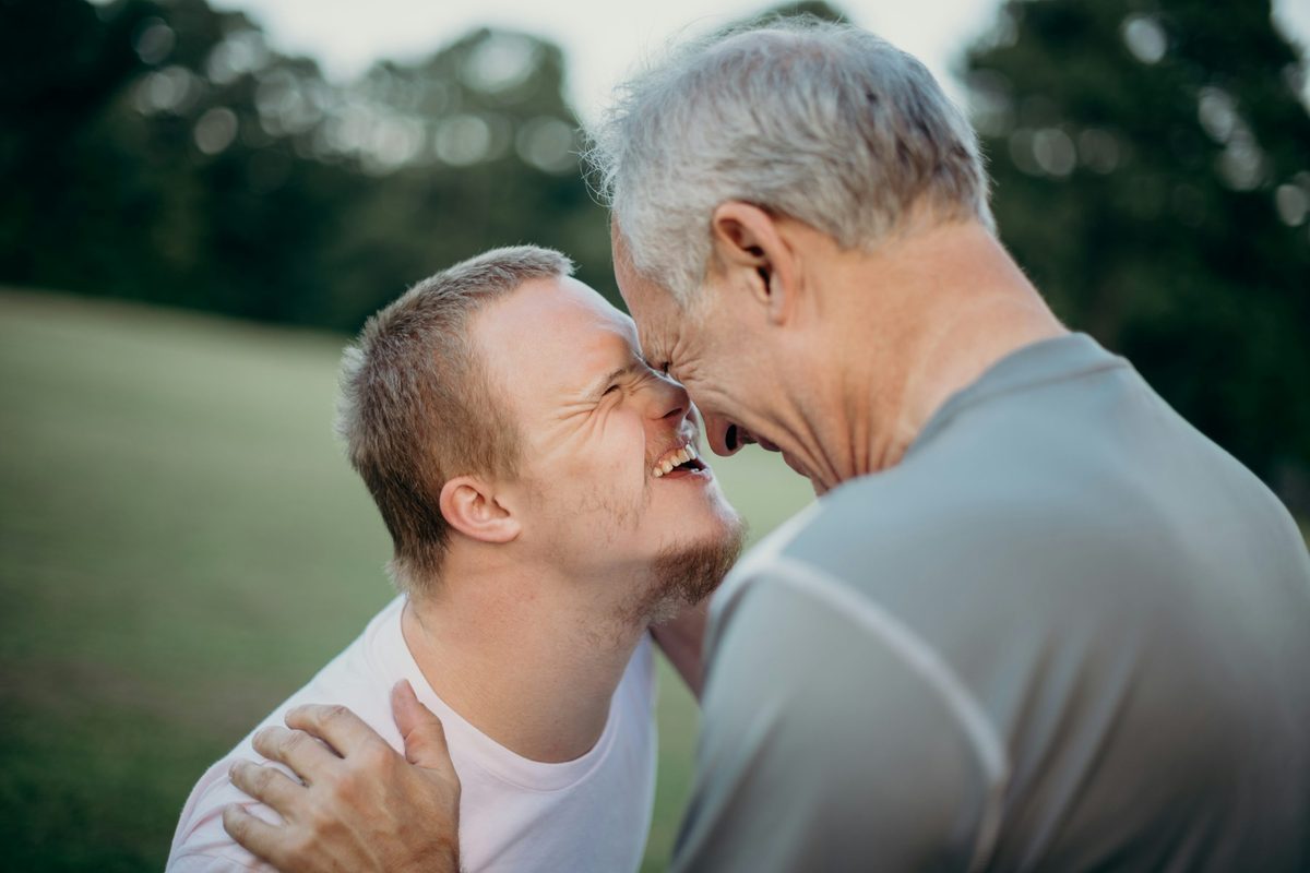 Adult son with Down syndrome sharing a happy moment with his father outdoors