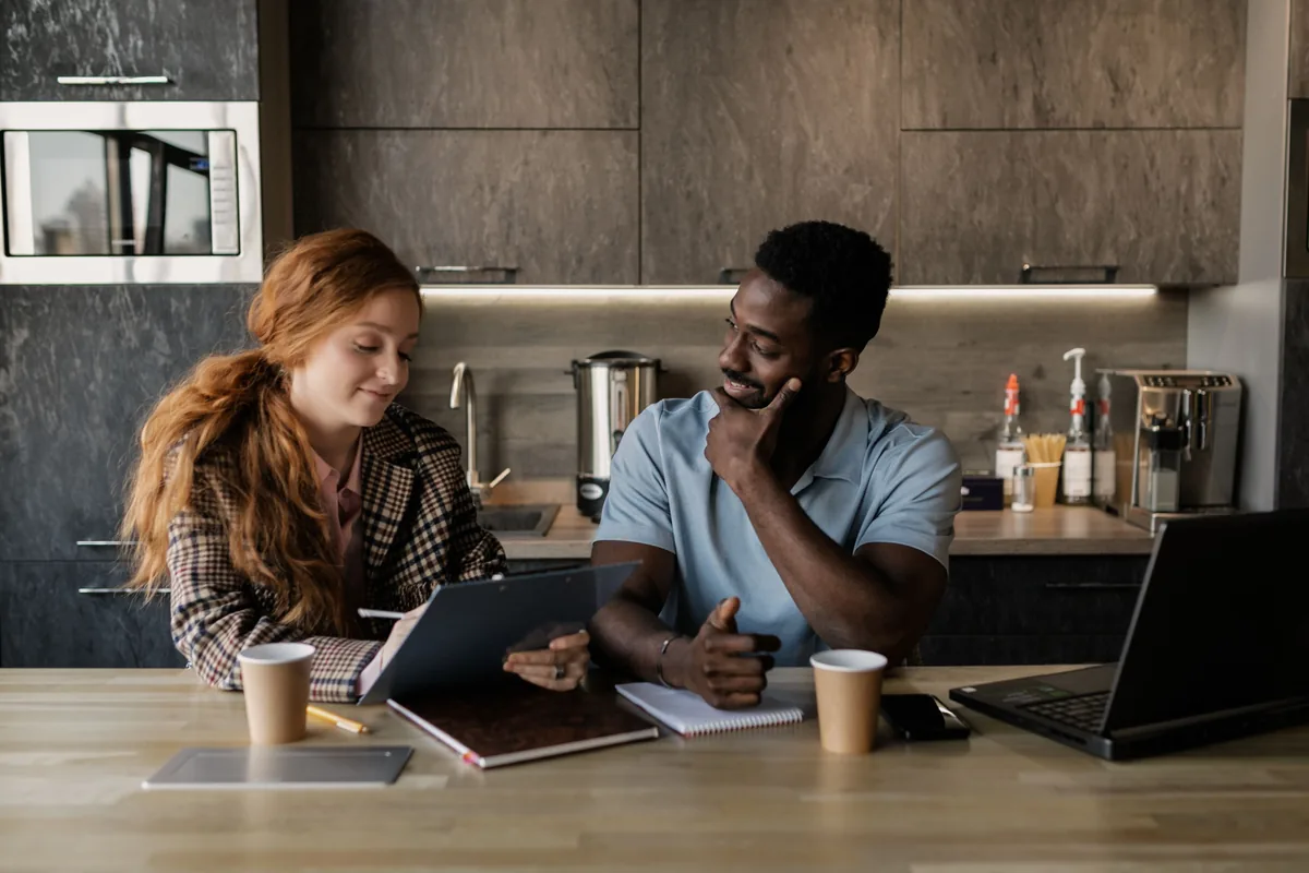 Two adults reviewing notes and a tablet together at a kitchen table