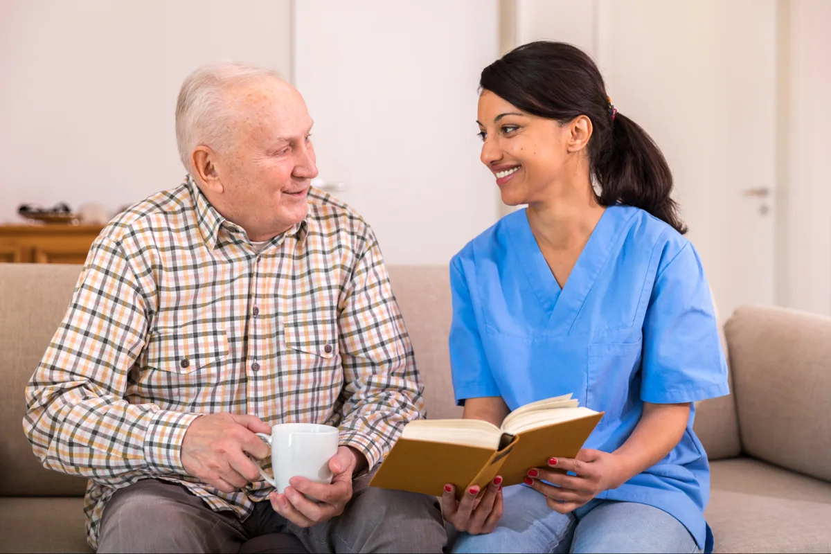 An older man and a woman sitting together with an open book